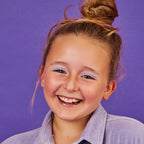Young girl with a big smile against a purple background