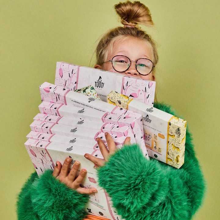 Person holding a stack of Tootie Fruity boxes against a green background