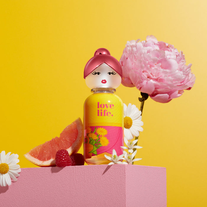 Perfume bottle with floral design and 'love life' text on a yellow background