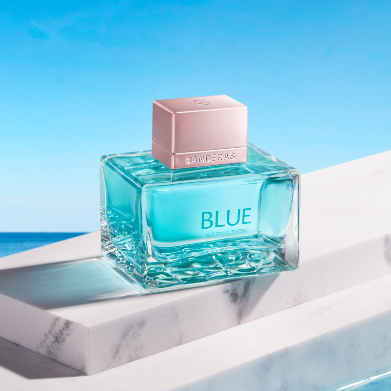 Blue perfume bottle on a marble surface with a blue background