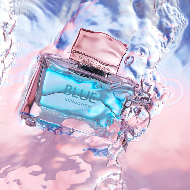 Perfume bottle labeled 'Blue Seduction' by Banderas on a water surface with ripples.