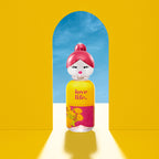 Perfume bottle with pink cap and yellow label featuring 'love life.' text, set against a bright yellow background with a blue archway.