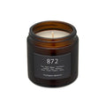 Brighton Beard white candle in a brown glass holder on a white background with neutral labels