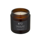 Brighton Beard white candle in a brown glass holder on a white background with neutral labels