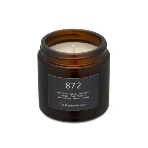Brighton Beard white candle in a brown glass holder on a white background with neutral labels