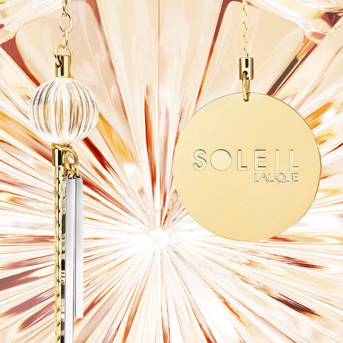 Gold pendant with 'Soleil Lalique' branding against a colorful abstract background