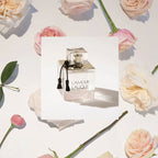 Lalique perfume bottle on a white card with pink roses in the background