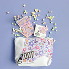 TOOT! cosmetic pouch with colorful packaging on a purple background