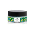 jar of exfoliating cream with Mrtyl design by Olimpia Zagnoli. Clear glass jar containing blue cream with green and yellow wrapping and black lid on white background.