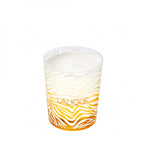 Candle in a Lalique container with wavy design on a white background