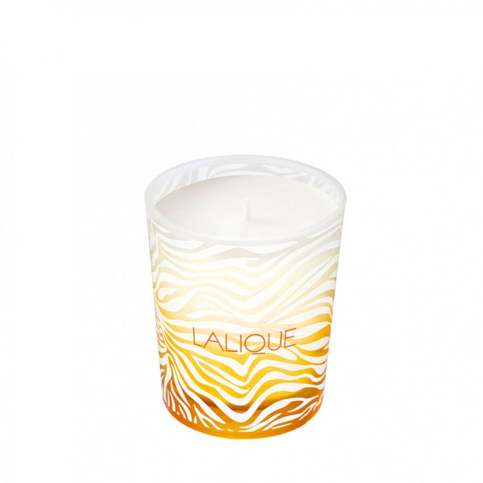 Candle in a Lalique container with wavy design on a white background