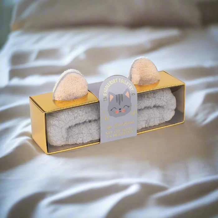 Cat-shaped spa headband with gold packaging on a soft surface
