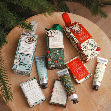 collection of festive handcare kits with christmas tree in background. on a piece of log