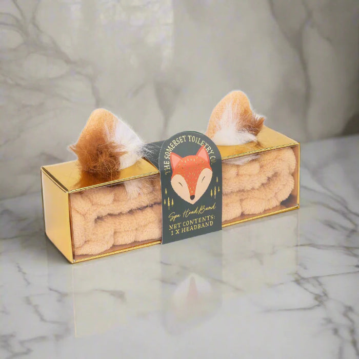 Two fox-shaped handbands in a gold box with a visible brand label on a marble surface.